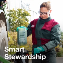 Person in protective gear using farming equipment with 'Smart Stewardship' text in foreground. - The text in the image reads: Smart Stewardship. Person in protective gear using farming equipment with 'Smart Stewardship' text in foreground. - The text in the image reads: Smart Stewardship.